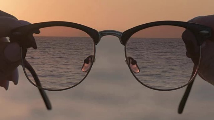 Cinemagraph-女人的手握着眼镜，蓝色海水的背景。