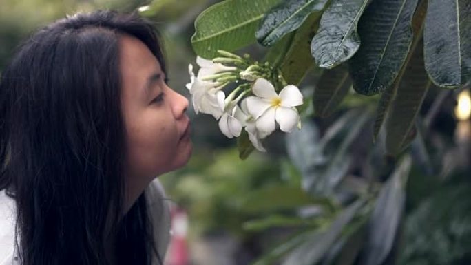 亚洲女人看着白花，闻起来