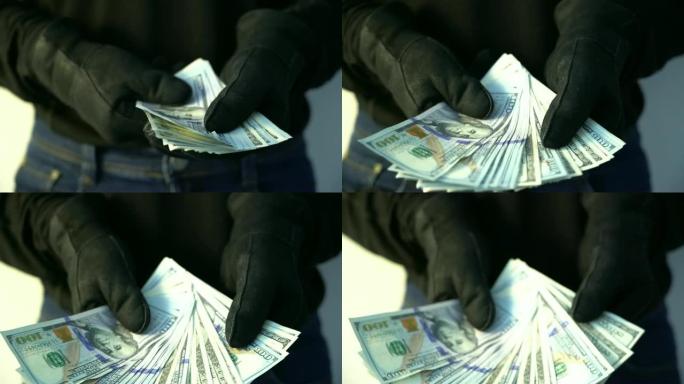犯罪概念男子穿着黑色皮手套拿着一堆钱