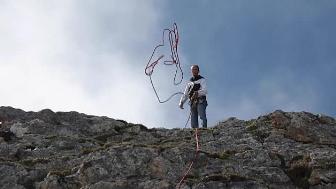 登山者的慢动作站在山顶上时会扔绳子。