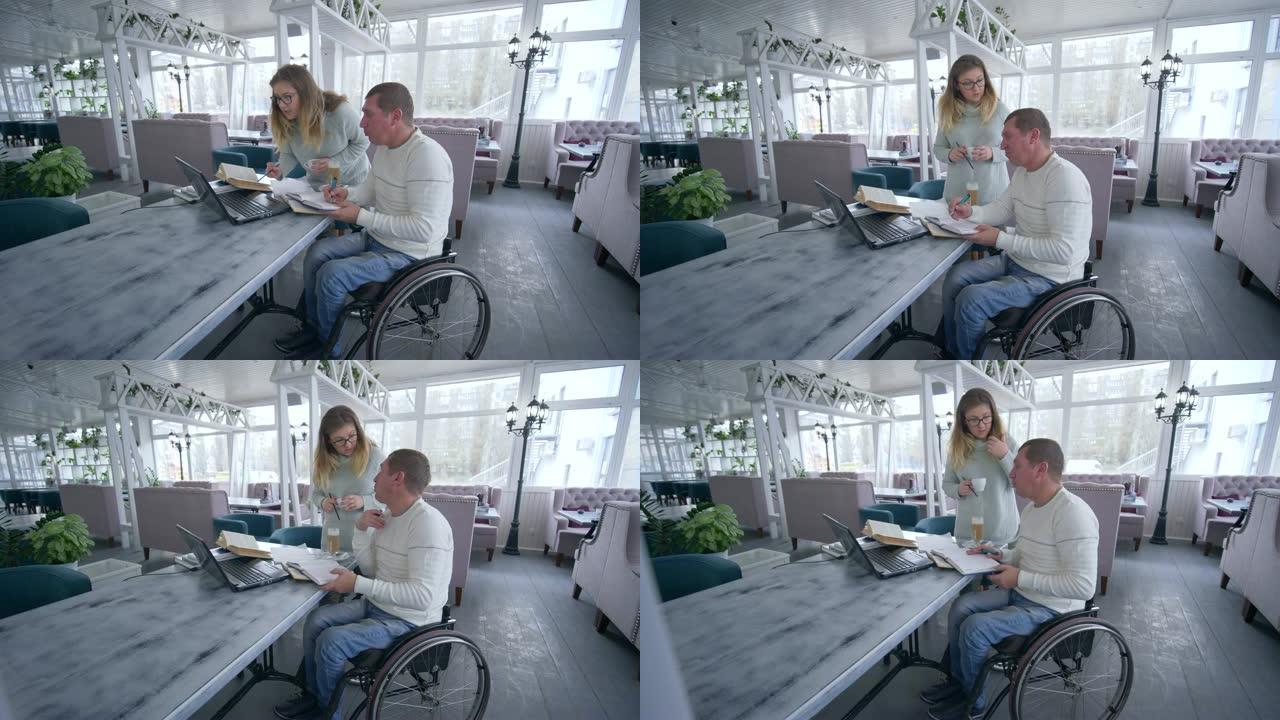 餐厅经理轮椅上的残障人士在笔记本电脑上工作时与女性讨论计划和发展商业想法