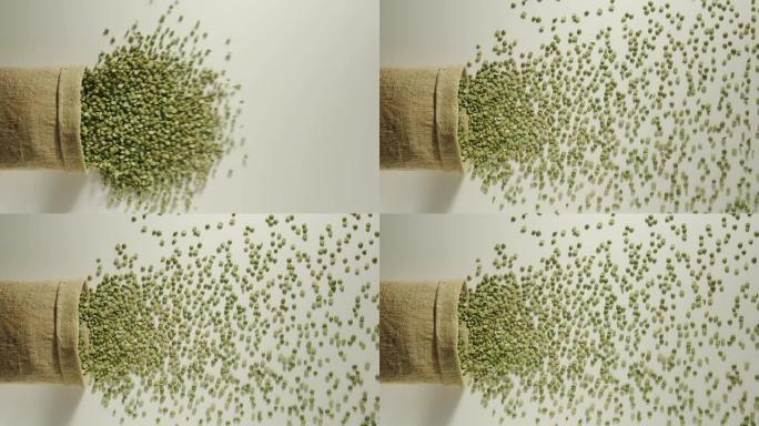 慢动作: 绿豌豆从掉落的麻袋中倒出-俯视图