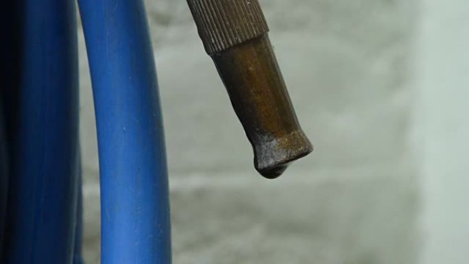 铁喷嘴和滚动蓝色橡胶管的水滴