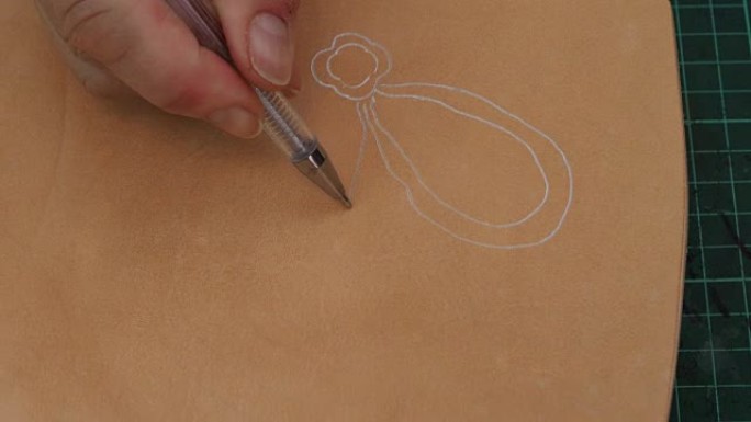 工匠在雕刻前用钢笔在粗糙的皮革上绘制花朵素描