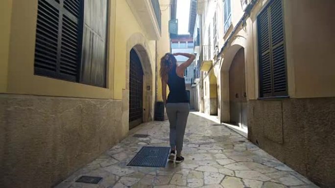 后视旅游妇女走在巴塞罗那狭窄的街道上穿着可爱的夏装享受欧洲暑假旅游度假冒险