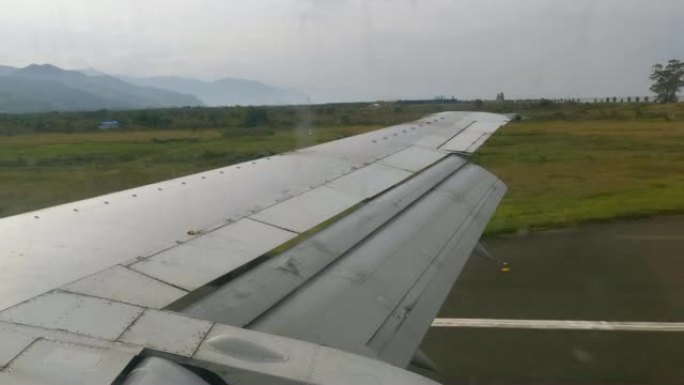 从飞机降落后沿机场跑道飞行的机翼上的窗户看