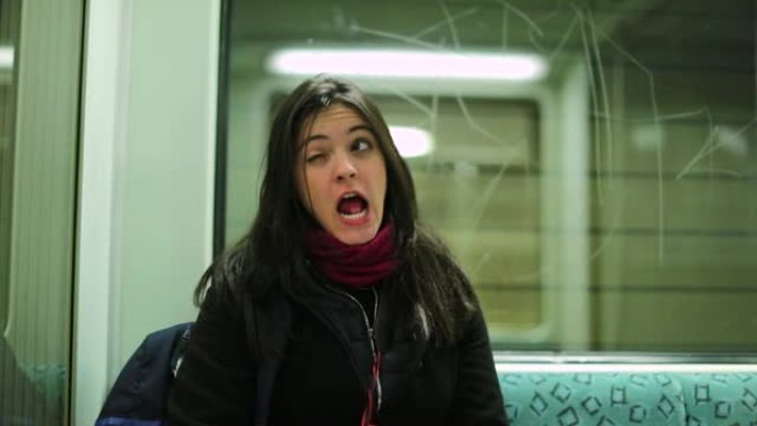 有趣的女孩在乘坐地铁时做着富有表现力的愚蠢的鬼脸看着镜头
