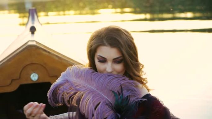 一位美丽的女人坐在缆车上，在日落的模糊背景上触摸带有狂欢节面具的紫色羽毛