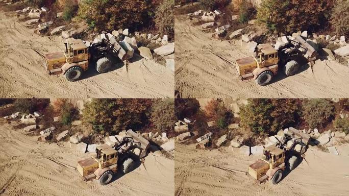 装有铲斗id的特殊设备的机器在采石场附近工作，采石场以沙子为背景。
