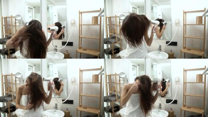 头发护理。女人在浴室用吹风机吹干长发