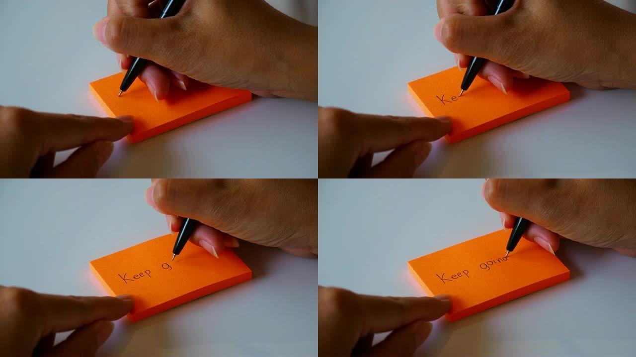 在橙色的便签纸或记事本纸上手写 “继续前进” 一词。运动4k镜头