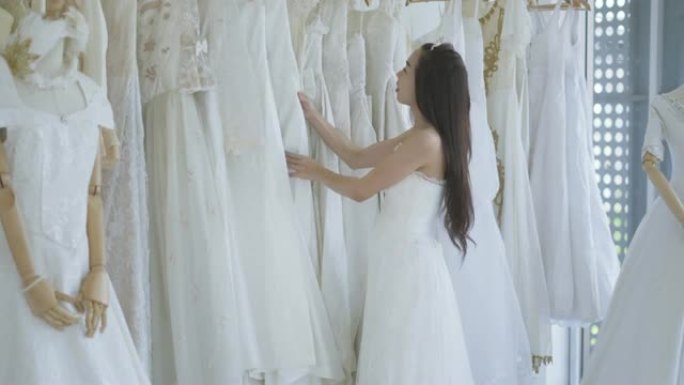 迷人的新娘在商店里选择婚纱，年轻漂亮的新娘穿着蓬松的礼服在工作室里摆姿势