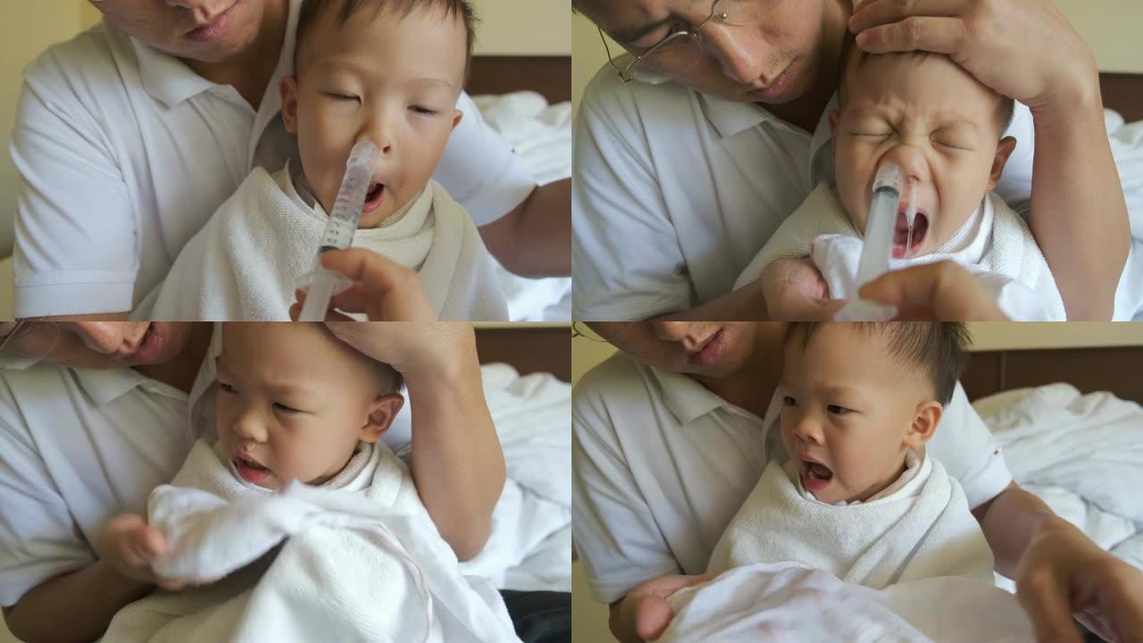 亚洲父母用注射器冲洗幼儿男童儿童鼻子，用于鼻腔冲洗