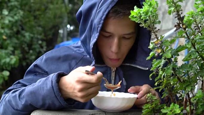 一个少年在雨中在外面吃饭