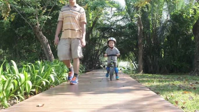 亚洲蹒跚学步的男孩戴着安全帽的孩子在阳光明媚的夏日学习骑第一辆平衡自行车