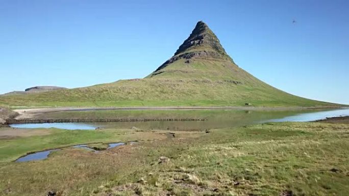 无人机拍摄了高加索夫妇的鸟瞰图，考虑着著名的kirkju费尔山峰，自然背景与草和山。春天在冰岛西部拍