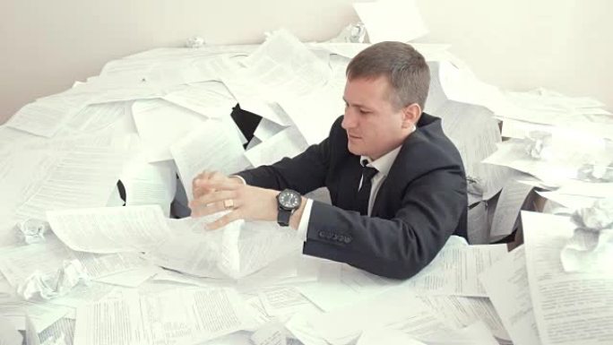 办公室员工无法应付文件的数量。一个疲惫的员工坐在文件的堆积如山，无法应付文件的数量