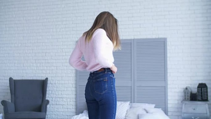 可爱的女人在卧室穿紧身牛仔裤