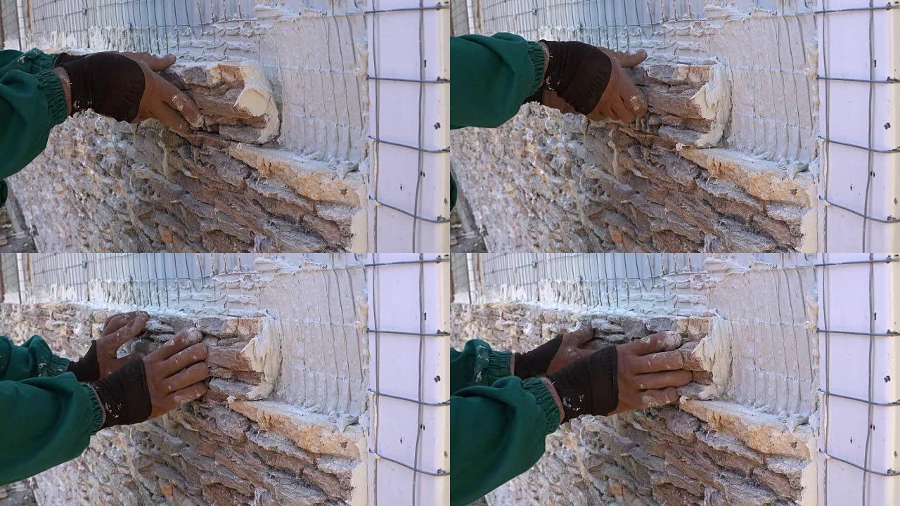 工人用观赏石瓷砖装饰墙壁，将瓷砖牢固地压制并固定成特殊的胶水和水泥混合物