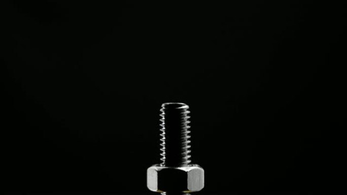 金属螺栓在黑色背景上拧紧螺母特写。维修施工概念