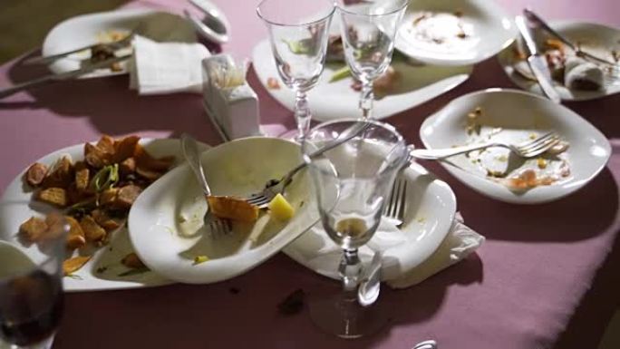 木制桌子上白色塑料盘中的食品残留物。