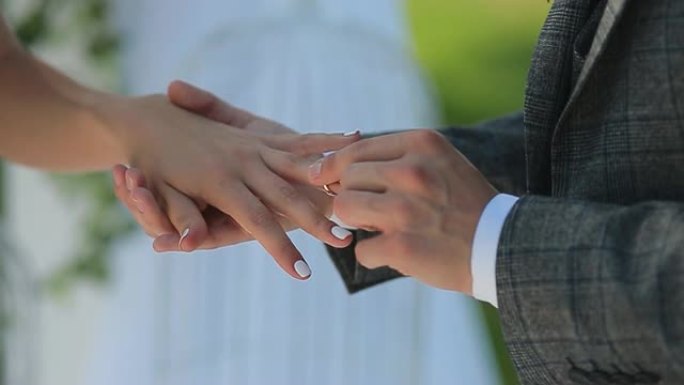 黄金结婚戒指和新婚夫妇的手靠近一个男人的手，在新娘的手指上戴上订婚戒指，在4k的红色数字电影相机上拍