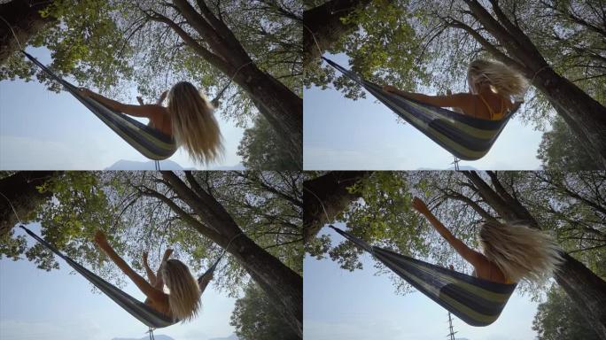 吊床上快乐的年轻女子在日落时摆动双腿，在大自然中尽情享受自由 -- 夏末。人们旅行快乐概念