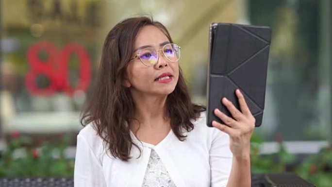 亚洲奢侈品成熟女性使用facebook live与数字平板电脑