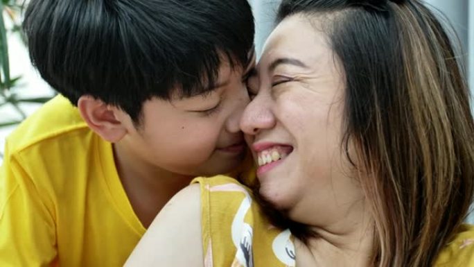 慢动作和亚洲快乐小男孩给他心爱的母亲紧紧拥抱的特写镜头。妈妈很高兴感受到儿子的爱