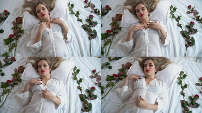 年轻女士的肖像，妆容明亮，鼻子穿孔。穿着短透明睡衣的女人躺在床上，带着红玫瑰。红玫瑰在靠近女性身体的