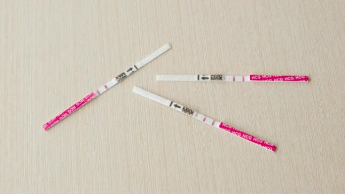 三个阳性妊娠试验结果，两张试纸放在桌子上。