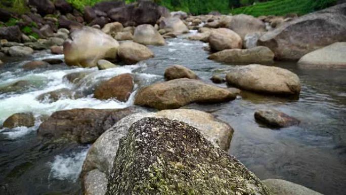 自然水流从山上经过许多岩石到乡村小村庄的河流。瀑布声降下来放松平静与和平。