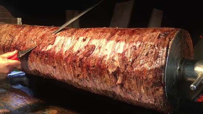 一位厨师用锋利的大刀切烤肉串，土耳其烤肉串在烤架上转动