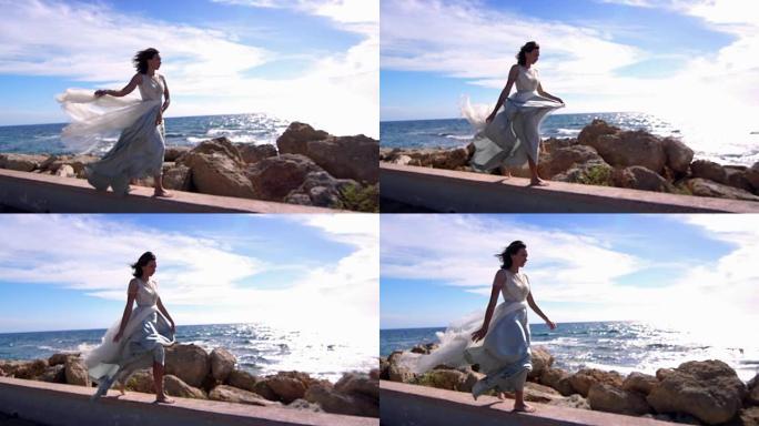 穿着裙子走在石滩上的优雅女人。夏季模特享受海洋景观
