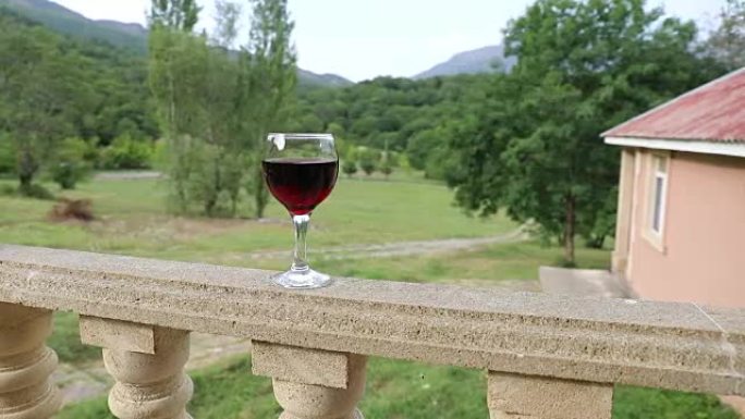 户外野餐环境，阳台上有葡萄酒或一杯葡萄酒，背景是绿色的田野和山脉。选择性聚焦