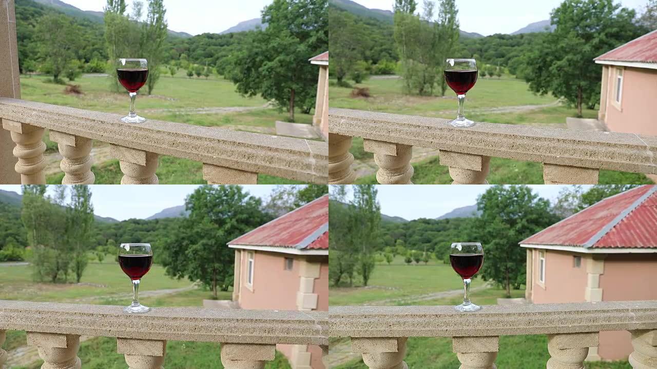 户外野餐环境，阳台上有葡萄酒或一杯葡萄酒，背景是绿色的田野和山脉。选择性聚焦