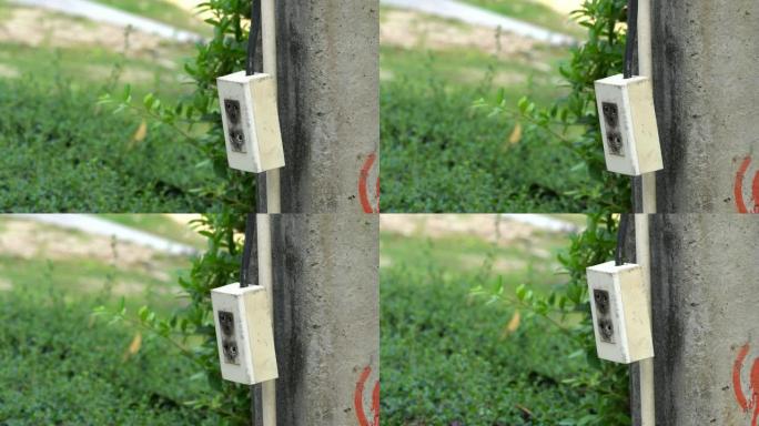 特写在混凝土电柱上悬挂和摆动插头的电源线背景