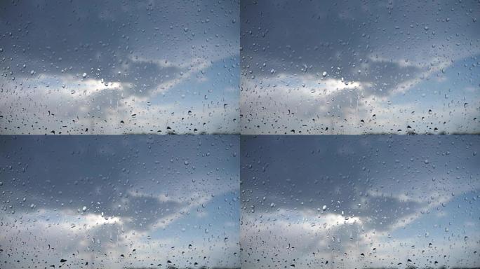 从雨滴到多云的天空的汽车挡风玻璃的角度。雨天关闭车辆窗玻璃上的水滴。