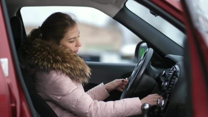 女孩上车，启动汽车，转动方向盘。秋。冬季4k慢动作