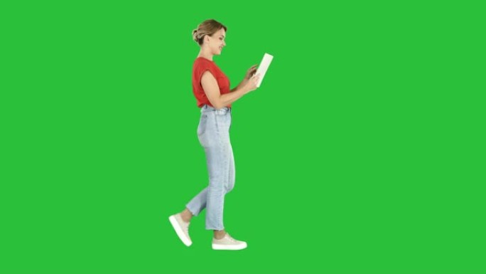 快乐的女人在绿色屏幕上与平板电脑一起行走，色度键