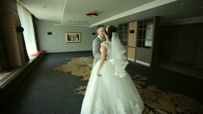 幸福的新婚夫妇在一个拥有美丽现代室内的房间里跳华尔兹舞。