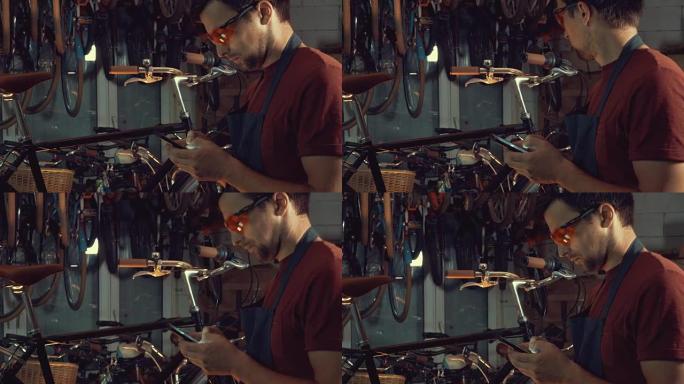 主题小型商务自行车维修。年轻的高加索黑发男子戴着安全镜，手套和fartukhhe使用手机技术，在自行