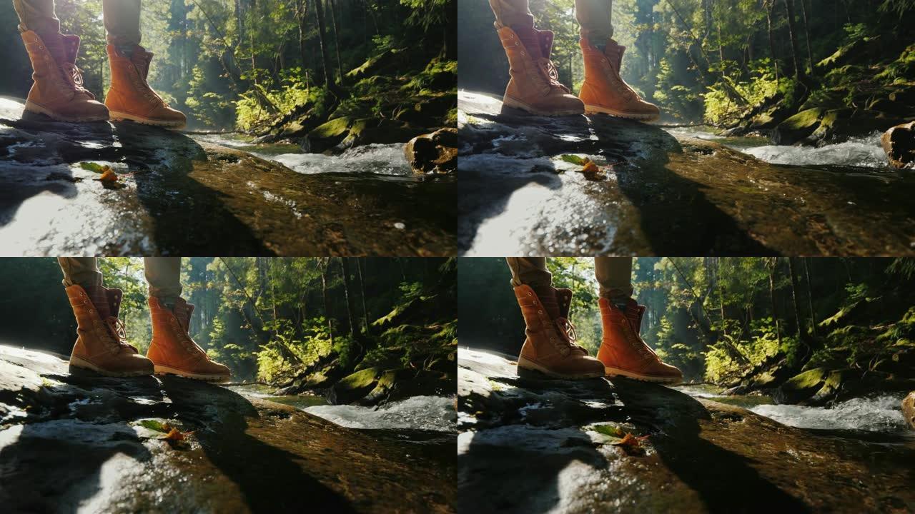 一名穿着靴子的游客站在山间小溪附近的滑石上
