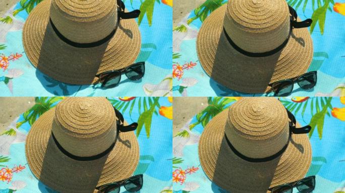 沙滩毛巾上的草帽和太阳镜