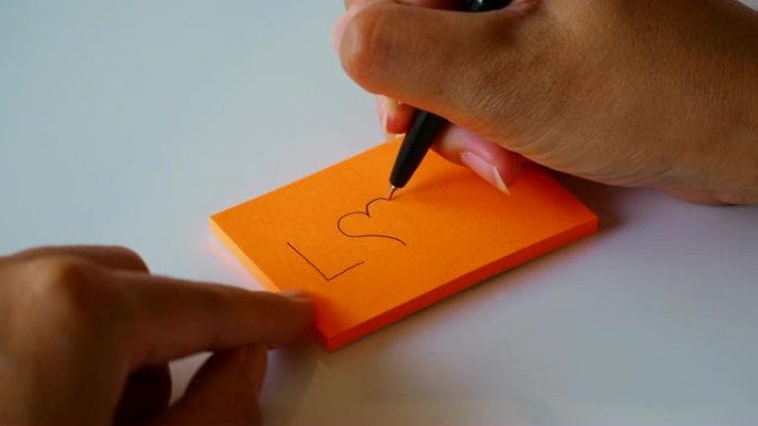 在橙色的便签纸或记事本上手写 “爱” 一词