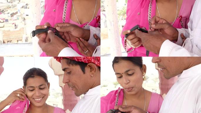 拉贾斯坦夫妇带着智能手表工作学习教学，分享穿着粉色纱丽和红色头巾在印度