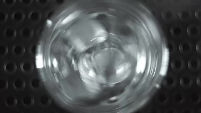 冰块落入鸡尾酒杯并滚动的宏观镜头。鸡尾酒制作。