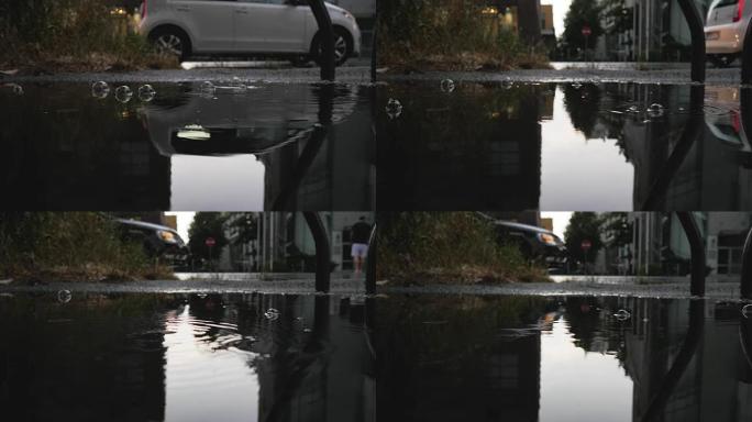 雨水在反映天空，建筑物和交通的水坑中形成气泡