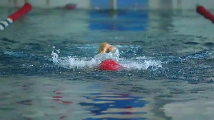 慢动作: 女运动员以蝶式游泳。水的飞溅向不同的方向散射。