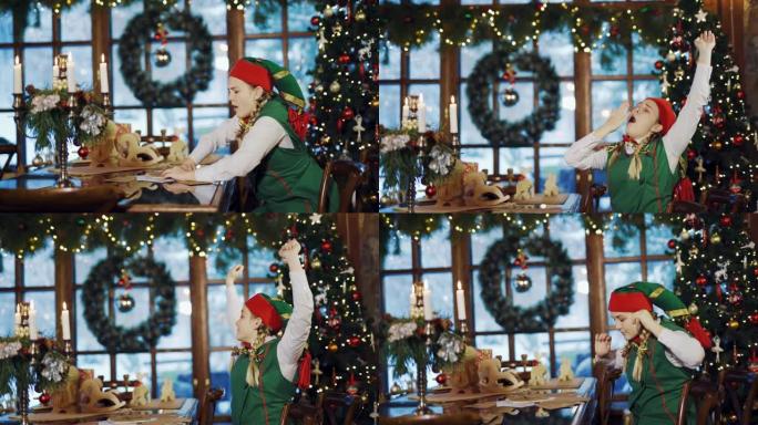 精灵女孩在餐桌旁醒来，在圣诞树，花环和窗户附近的新年花圈的背景上有祝贺信，礼物和蜡烛。